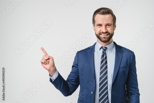 Toothy smile of handsome caucasian successful confident businessman in formalwear suit pointing showing copyspace free space isolated in white background