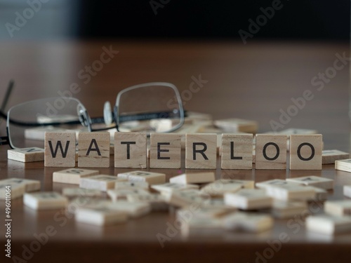 waterloo word or concept represented by wooden letter tiles on a wooden table with glasses and a book