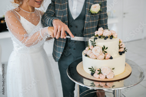 The wedding cake. Stylish happy newlyweds, elegant satisfied bride. Newlyweds gathering