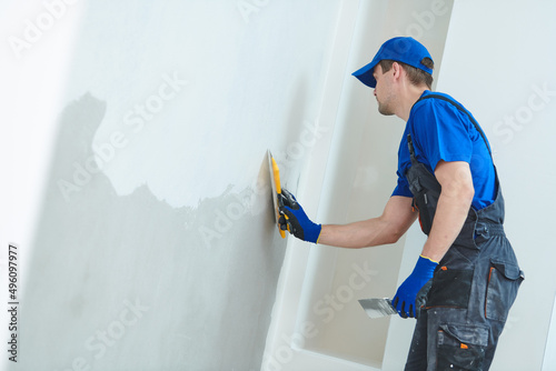 refurbishment. Plasterer worker spackling a wall with putty