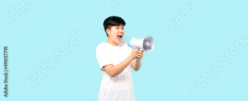 tomboy Asian over isolated blue background shouting through a megaphone in studio With copy space.