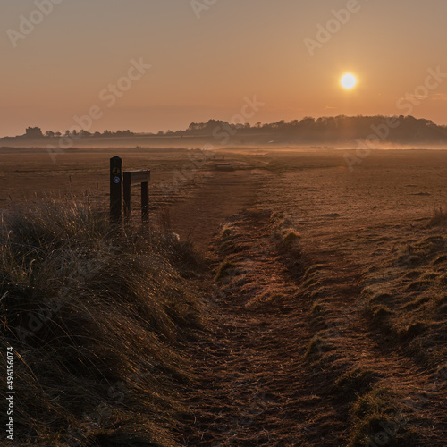 The low winter sun creates a painterly effect across the pastoral scene approaching the beach