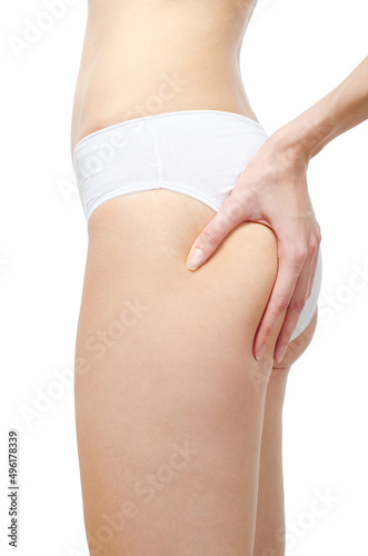 Young woman in underwear squeezing skin to show cellulite and stretch marks isolated on white background.