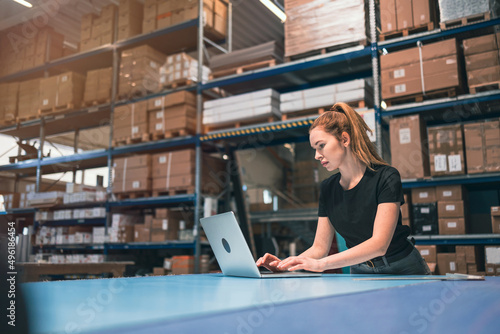 Woman using laptop at warehouse 