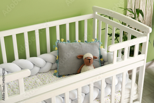 Cozy baby crib near color wall in stylish children's room