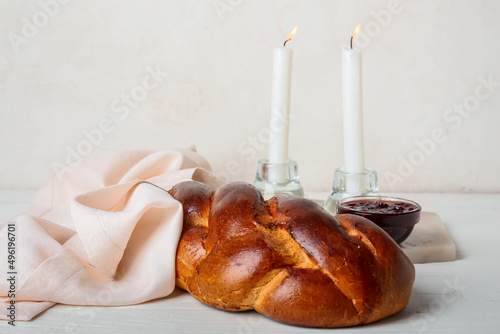 Traditional challah bread with glowing candles on white background. Shabbat Shalom