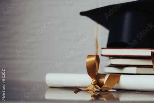 Birrete con libros apilados y diploma al lado. Concepto de graduación.