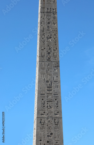 Egyptian obelisk with engraved hieroglyphs on blue sky background