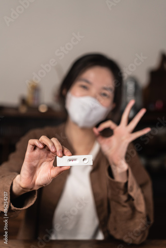 Close up of Asian woman holding the antigen covid test kit happily, showing negative result 