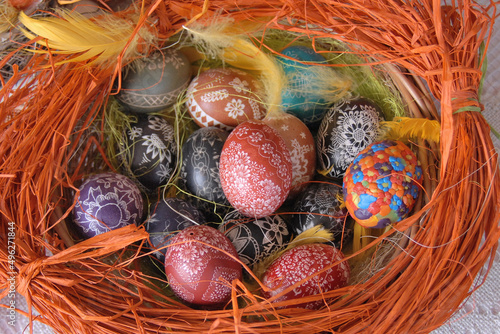 A traditional dyed colourful Easter egg in a basket with feathers in Poland called pisanka or kroszonka