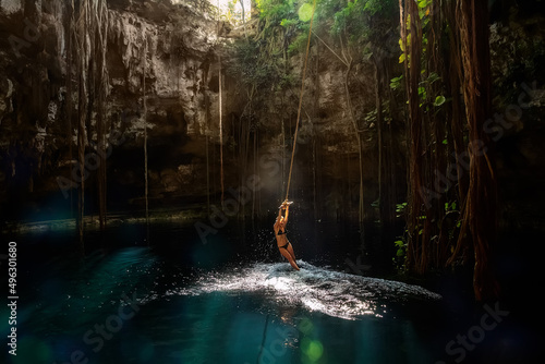 Cenote Ik-Kil Yucatan. Girl on a bungee. Mexico.
