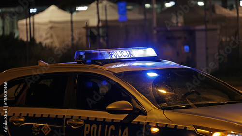 Radiowóz policji na sygnale wieczorem w mieście alarmowo do wypadku na światłach.