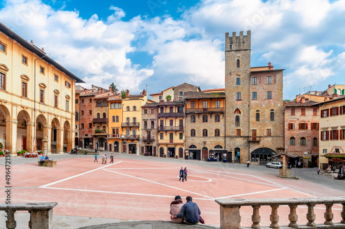 Couple sitting on the ground in the famous Piazza Grande square in the historic center of Arezzo, Italy