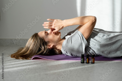 woman meditates with essential oils while lying on a yoga mat. Ultrasonic and humidifying aromatherapy. Meditation fitness and exercise concept copy space. Active lifestyle. home or gym club