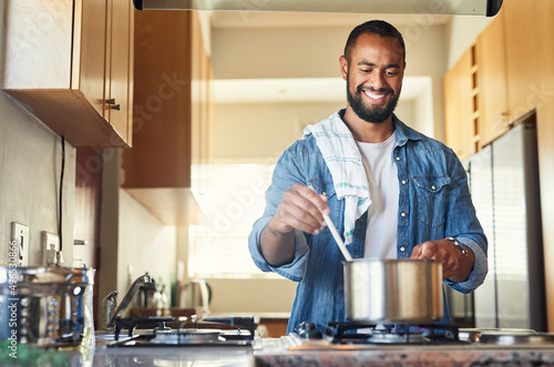 I cant wait until its done. Shot of a young man cooking at home.