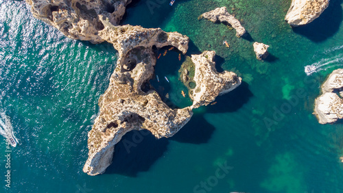 Aerial drone shot of kayaks and boats passing around magical Ponta da Piedade limestone cliffs. Exploring caves and tunnels of Lagos, Algarve, South of Portugal. Travel and adventure. Nomad life. 