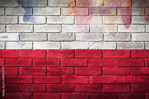 Flaga polski namalowana na ceglanym murze. The Polish flag painted on a brick wall.