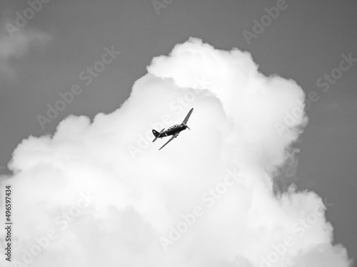 czarno białe zdjęcie starego jednopłatowca na tle chmur podczas pokazu lotniczego