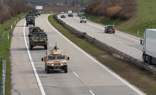 Army military convoy passes in Czech Republic. Wheeled armored vehicles drive on highway .