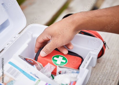 Everything he needs to treat your injuries. High angle shot of an unrecognizable male paramedic looking in his first aid kit while standing outside.