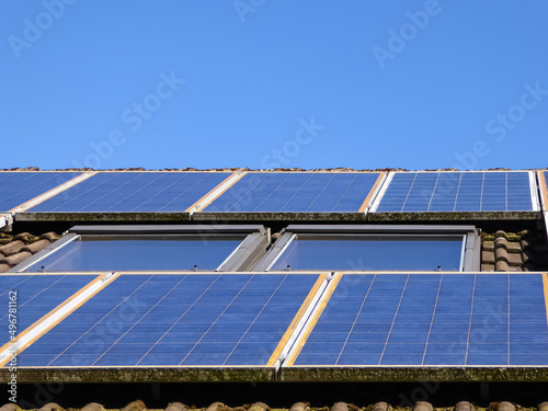 Altanlage. Über 10 Jahre alte Solarpanele. Photovoltaikanlage auf dem Dach eines Einfamilienhauses neben schrägen Dachfenstern. Die Solarmodule wurden um das Fenster herum montiert. Old solar modules.