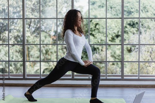 Young woman doing front lunges or squat exercise at home