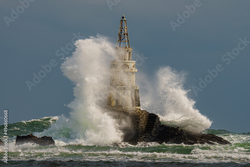 Old rusty lighthouse in the Black Sea with giant waves crashing on it in Ahtopol, Bulgaria