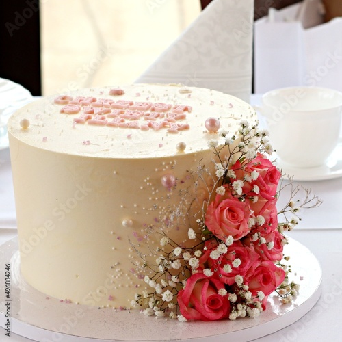 Elegancki tort w kolorze kremowym ozdobiony różami