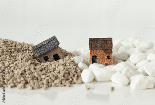 Two miniature houses in sand and rock isolated on white background with copy space. A close-up. The gospel parable of Jesus Christ for obedience and faith in God. Christian concept.