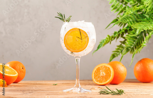 Gin tonic cocktail long drink with dry gin, bitter tonic, orange, rosemary and ice, bar tools. Wooden table background with copy space