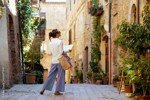 stylish woman with map enjoying promenade in Tuscany, Italy