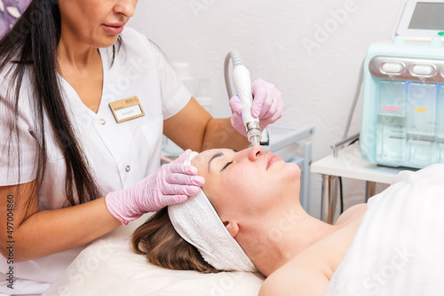 Beauty salon. The cosmetologist makes a hydra peeling procedure for the client in the nose area. Close up. The concept of professional skin care