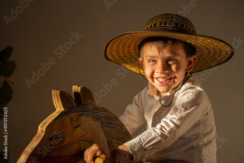 Niño juguetón feliz sonriente expresivo posando con sombrero campesino vaquero disfrutando