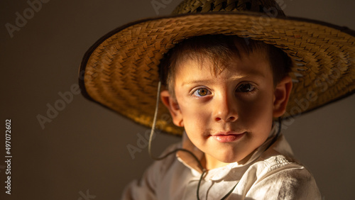 Niño juguetón feliz sonriente expresivo posando con sombrero campesino vaquero disfrutando