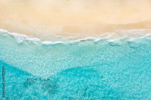 Summer nature landscape. Aerial view of sandy beach and ocean with waves. Beautiful tropical island, white empty beach and sea waves seen from above, top aerial view. Tranquil, relaxing scenic
