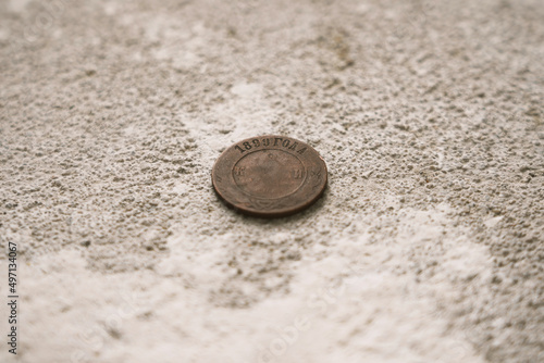 photograph of an 1899 coin in a poorly preserved state on a concrete gray floor