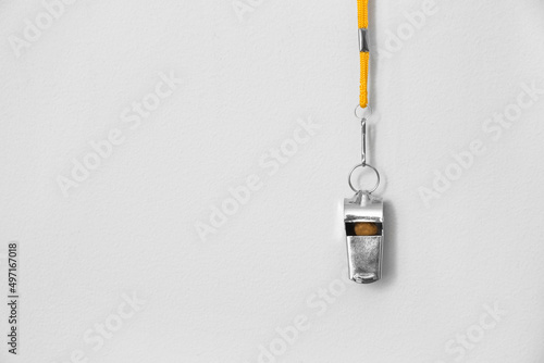 Lifeguard's whistle hanging on light wall, closeup