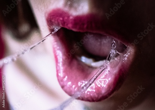 Upclose woman's mouth with saliva and red lipstick