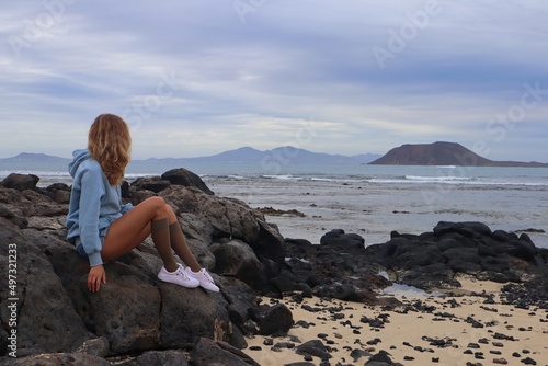 Kobieta siedząca bokiem nad oceanem w pochmurny dzień