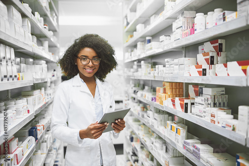 We have all the medication anybody would ever need. Portrait of a cheerful young female pharmacist standing with a digital tablet while looking at the camera in a pharmacy.