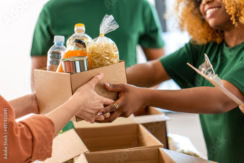 charity, donation and volunteering concept - close up of volunteers giving box of food at distribution or refugee assistance center