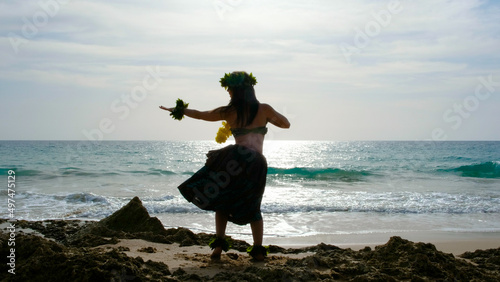 Woman rests and poses happily on the beach wearing the typical hula dance costume. Hawaiian dance beauty. Exotic girl. Silhouette of woman dancing hula.