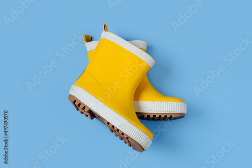 A pair of child yellow rain boots on blue background