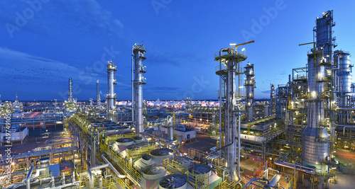 refinery - chemical factory at night with buildings, pipelines and lighting - industrial plant