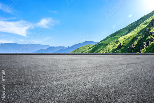 Empty asphalt road and green mountain nature landscape under blue sky. Road and mountains background.