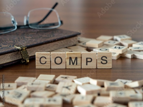 the acronym comps for comparable company analysis word or concept represented by wooden letter tiles on a wooden table with glasses and a book