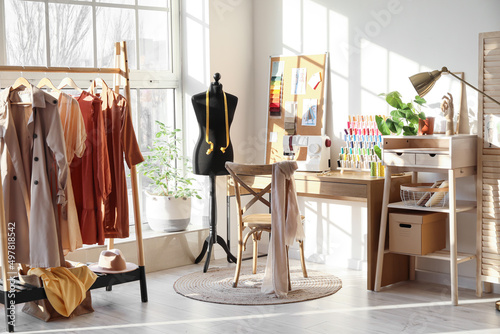 Interior of stylish atelier with tailor's workplace, mannequin and rack