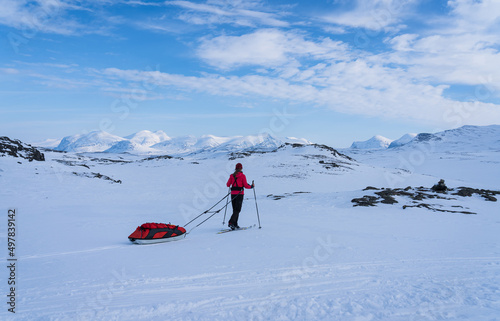 Female cross country skier with pulka (sled) in the snow in Lapland, Sweden.