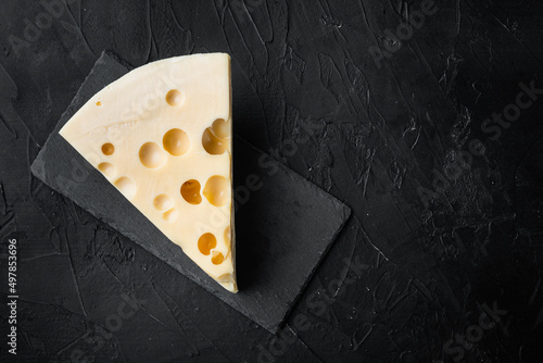 Maasdam cheese, on black stone background, top view flat lay, with copy space for text