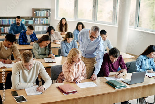 Senior teacher assists his students during a class at college classroom.